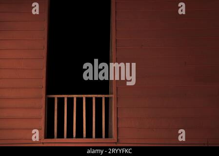 Balkon aus Holz mit dunklen Zimmer in Fenster. Haus im thailändischen Stil. Haunted house Hintergrund Konzept. Stockfoto