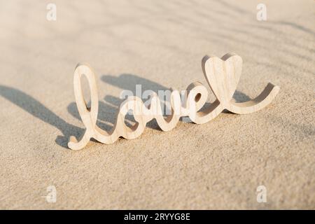 Hölzerne Wort Love auf Sandstrand Hintergrund. Konzept des romantischen Feiertags, Vorschlag, Valentinstag Grußkarte, Pos. Stockfoto