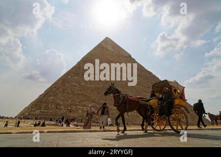 Die zweirädrige Pferdekutsche fährt vor einer Pyramide, Pferd, Menschen, Touristen, Sonne, die Khafre-Pyramide in Gizeh, Ägypten Stockfoto