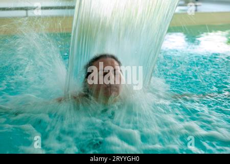 Frauengesicht Entspannen Sie sich in einem Hydromassage-Pool mit fallendem Wasser bei langer Exposition in der Schweiz Stockfoto