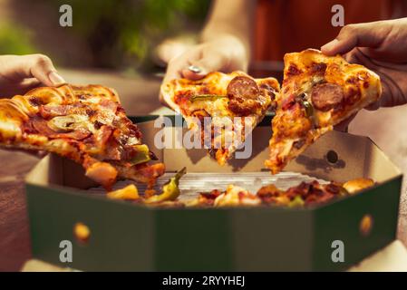 Nahaufnahme der in Scheiben geschnittenen heißen Pizza, die von Freundschaftsmenschen Hände für die Feier hält. Pizza Margarita Küche mit Käse und s Stockfoto