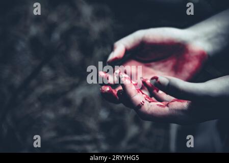 Nahaufnahme von blutigen Händen im dunklen Waldhintergrund. Horror- und Geisterkonzept. Kriminalität und Mordkonzept. Halloween-Tag und Sack Stockfoto