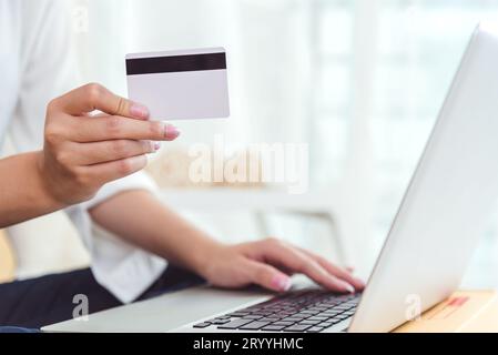 Frau hält eine Kreditkarte für Online-Shopping oder die Bestellung von Produkten über das Internet, wenn sie einen Laptop verwendet. Geschäft und Zahlung Co Stockfoto
