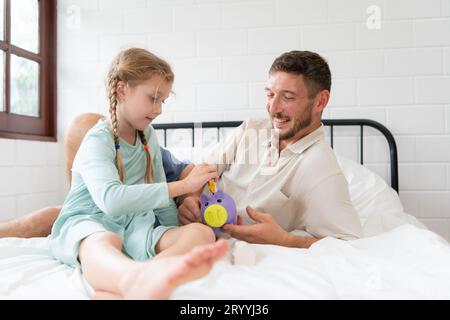 Vater lehrt der Tochter, wie man Geld spart, damit das Kind die Fähigkeiten hat, Geld zu verwalten und zu leben Stockfoto