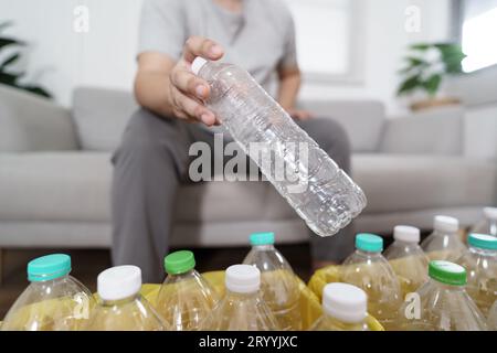Recyceln Sie den umweltfreundlichen Zero Concept-Mann, der leere Plastikflasche in den Recyclingbehälter mit gelben Mülltüten zu Hause wirft Stockfoto