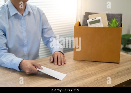 Ich schicke den Rücktrittsbrief an den Boss und halte Zeug, kündige Depression oder trage Pappkarton am Schreibtisch im Büro Stockfoto