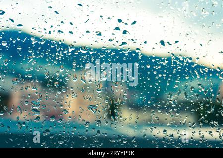 Regen tropft mit Sonnenuntergang auf die Glasoberfläche. Tropfen auf Glasspray auf Fensterhintergrund für dunkle textÂ selektive Fokussierung Stockfoto