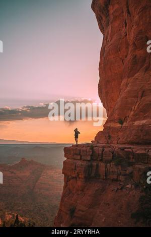 Junge Wanderer am Rande einer Klippe am Cathedral Rock in Sedona, Arizona. Blick vom szenischen Cathedral Rock in Sedona mit bl Stockfoto