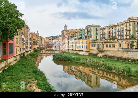 Farbenfrohe gelbe und orangene Häuser und Brücke Pont de Sant Agusti spiegeln sich im Fluss Onyar in Girona, Katalonien, Spanien. Ch Stockfoto