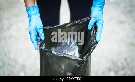 Freiwillige Wohltätigkeitsorganisation womanÂ Hand hält Müllbeutel und Plastikflaschenmüll zum Recycling für die Reinigung im Park Freiwilligendienst Stockfoto