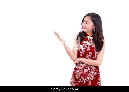 Junge asiatische Schönheitsfrau trägt Cheongsam und präsentiert mit Handgesten in chinesischem Neujahrsfest auf isoliertem Witz Stockfoto