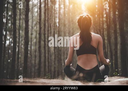 Rückansicht einer wunderschönen Frau, die in friedlichem Naturwald Yoga spielt. Lifestyle und Meditation. Gesunde und geistige tr Stockfoto