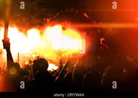 Rockkonzert mit Silhouetten, Menschen in fröhlicher Geste und Hände heben, um Sänger aufzuheitern. Unterhaltung und Menschenkonzept Stockfoto