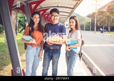 Drei junge asiatische Campus-Studenten genießen es, gemeinsam Nachhilfe zu geben und Bücher zu lesen. Freundschaft und Bildungskonzept. Campus-Schule und Stockfoto