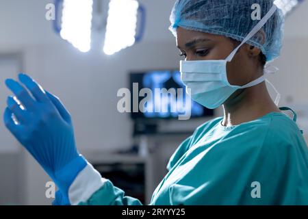 afroamerikanische Chirurgin mit Operationskittel und Handschuhen im Operationssaal im Krankenhaus Stockfoto