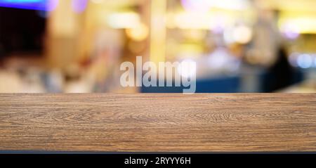 Leerer dunkler Holztisch vor dem abstrakten, verschwommenen Bokeh-Hintergrund des Restaurants. Kann zur Anzeige oder Montage Ihres PR Stockfoto