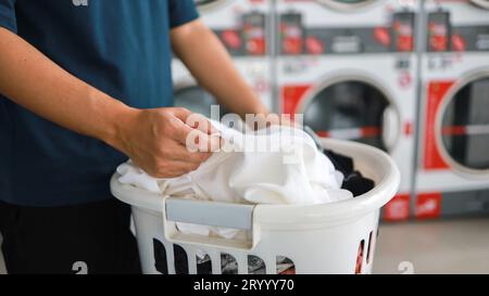 Hausmann mit Korb und schmutziger laundryÂ gewaschener Kleidung im Waschraum. Waschen machineÂ im Wäschereigeschäft Stockfoto