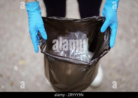 Freiwillige Wohltätigkeitsorganisation womanÂ Hand hält Müllbeutel und Plastikflaschenmüll zum Recycling für die Reinigung im Park Freiwilligendienst Stockfoto