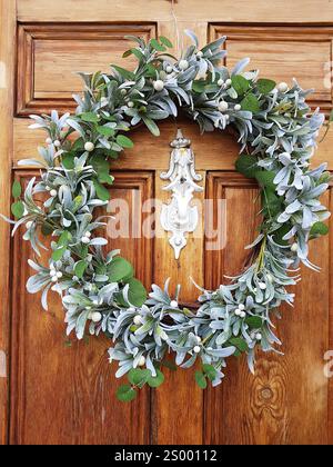 Ein weihnachtlicher Blumenkranz an einer traditionellen Holztäfeltür. Stockfoto