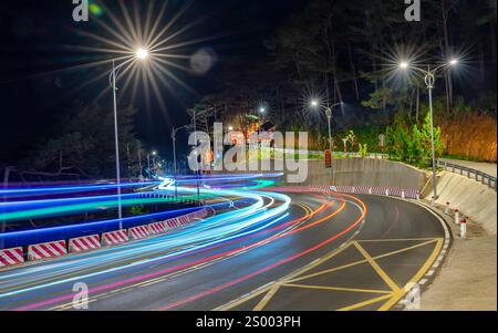 Nachtszene am neu verbreiterten gekrümmten Pass in da Lat, Vietnam, beleuchtet von den Scheinwerfern vorbeifahrender Autos in einer dunklen Nacht, um den Verkehr zu fördern Stockfoto