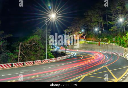 Nachtszene am neu verbreiterten gekrümmten Pass in da Lat, Vietnam, beleuchtet von den Scheinwerfern vorbeifahrender Autos in einer dunklen Nacht, um den Verkehr zu fördern Stockfoto