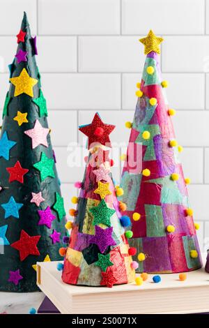 Farbenfrohe Tissue-Papier-Kegel-Weihnachtsbäume mit Sternen und Pompons Stockfoto