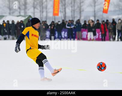 (241223) -- JILIN, 23. Dezember 2024 (Xinhua) -- Li Faxiong vom Fußballteam der „Village Super League“ des Bezirks Rongjiang aus der Provinz Guizhou im Südwesten Chinas 3000 spielt am 23. Dezember 2024 während eines Freundschaftsfußballspiels gegen die Fußballmannschaft des Bezirks Fengman der Stadt Jilin, die auf dem Schneefeld im Dorf Nanyang in der Stadt Shulan, nordöstlichen Chinas, ausgetragen wurde. Die Fußballmannschaft des Bezirks Fengman von Jilin City gewann den Stockfoto