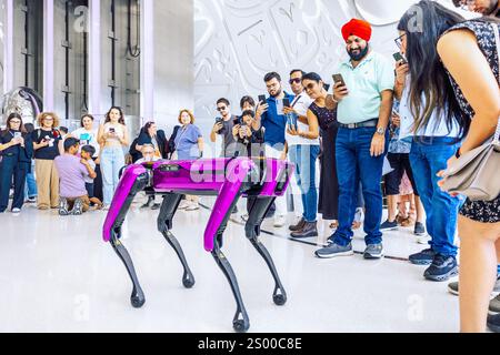 Dubai, VAE - 9. Dezember 2024: Modernes futuristisches Museum der Zukunft. Schneeweiße Inneneinrichtung im Museum mit arabischer Schrift an den Wänden. Roboterhund spielt mit Besuchern Stockfoto