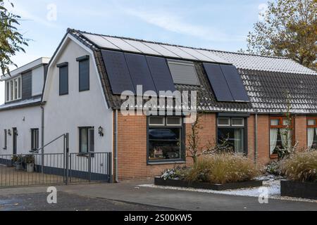 Leerdam, Niederlande. 21. November 2024. Private Solarpaneele mit Schnee und eine Hälfte ohne Schnee auf einem Familienhaus auf dem Dach im Winter. Stockfoto