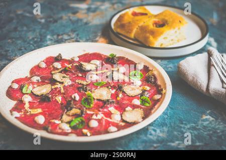 Angus Beef Carpaccio in dünne Scheiben geschnittenes, rohes australisches Rindfleisch rasiert frische saisonale Trüffel, italienisches Trüffelpüree, in Scheiben geschnittener Grana Padano Käse, Brot auf dem Stockfoto