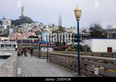 San Francisco, CA, USA. 22. April 2012: Touristen spazieren an einem nebeligen Pier in San Francisco mit dem Coit Tower im Hintergrund. Stockfoto