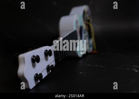 Buntes Ukulele-Spielzeug für Kinder auf dunklem Hintergrund. Musikkonzept. Stockfoto