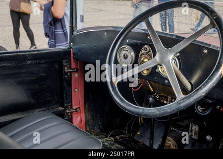 Lissabon, Portugal - 15. Oktober 2023: Schwarzer Innenraum mit Lenkrad und Armaturenbrett des alten Ford Model A Tudor Limousine. Lenkrad aus Holz und Armaturenbrett aus Vollmetall im selektiven Fokus. Stockfoto