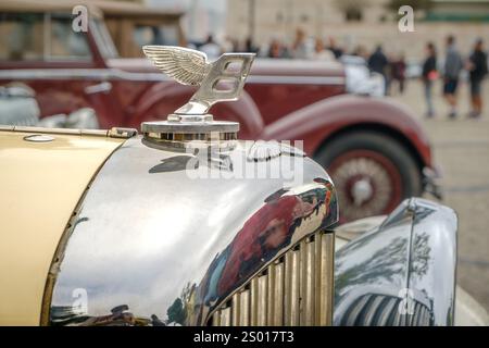 Lissabon, Portugal - 15. Oktober 2023: Nahaufnahme und selektiver Fokus auf das Bentley Wings Flying B Maskottchen-Verzierung oder Motorhaubenabzeichen aus den 1930er Jahren vor anderem Autohintergrund. Stockfoto