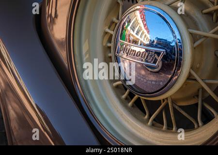 Lissabon, Portugal - 29. September 2024: Nahaufnahme und selektiver Fokus auf Ersatzdrahtrad und Radmittelkappe mit Plymouth-Logo am sonnigen Tag. Urbanes Ambiente mit Reflexen, Vintage-Look. Plymouth Chrysler Motors, Chrysler Corp, USA Stockfoto