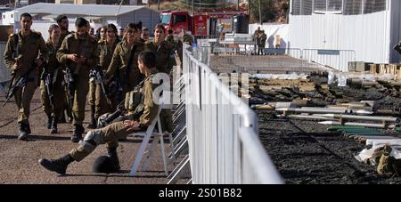 Amirim, Israel. Dezember 2024. Ein israelischer Soldat sitzt Wache, während andere die gewaltige Ausstellung gefangengenommener Hisbollah-Rüstungen einschließlich einer großen Ausstellung von Raketen verschiedener Größe (rechts) in der israelischen Armeebasis unweit der Grenze zum Südlibanon am 23. Dezember 2024 überprüfen. Die IDF stellte etwa 86.000 Gegenstände vor, die im Südlibanon südlich des Litani-Flusses während der Kämpfe gegen die Hisbollah-Truppen, die am 1. Oktober 2024 begannen, gefangen genommen wurden. Foto von Jim Hollander/UPI Credit: UPI/Alamy Live News Stockfoto