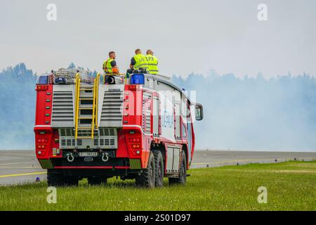 Liepaja, Lettland, 16. Juni 2024: Flugzeugfeuerwehr mit einer Besatzung im Dienst, roter moderner Feuerwehrwagen auf der Start- und Landebahn des Flughafens Stockfoto