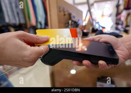 Frau, die mit kontaktloser Kreditkarte bezahlt, den Einzelhandel am Verkaufsterminal des Bekleidungsgeschäfts abschließt, eine praktische Transaktion erlebt Stockfoto