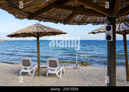 Leeres Strandcafé ohne Besucher nach Ende der Saison, Schilfsonnenschirme, leere Liegen, Adria, Kroatien Stockfoto