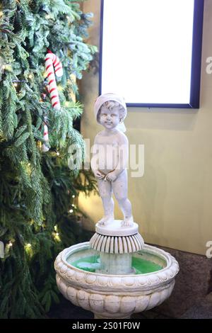 Ein eleganter Gartenbrunnen mit einer wunderschönen Cherub-Statue in festlicher Atmosphäre Stockfoto