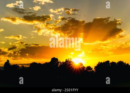 Ein heller goldener Sonnenuntergang mit der Sonne, die am Horizont absinkt und den Himmel mit Farbe erfüllt. Stockfoto