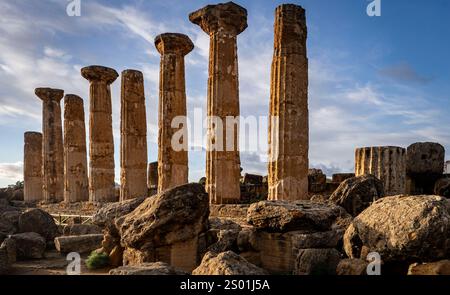 Antike griechische Ruinen mit hohen, verwitterten Säulen vor einem bewölkten Himmel, umgeben von großen Steinen und archäologischen Überresten. Stockfoto