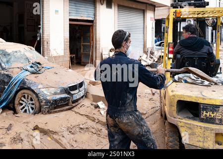 DANA-Flutungseffekte. Überschwemmungseinflüsse, Valencia, Spanien. Freiwillige und Einheimische bei Reinigungsarbeiten in Paiporta. Das Auto steckt im Schlamm fest Stockfoto