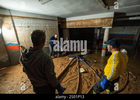 DANA-Flutungseffekte. Überschwemmungseinflüsse, Valencia, Spanien. Arbeiter pumpen Schlamm in einer Garage in Paiporta Stockfoto