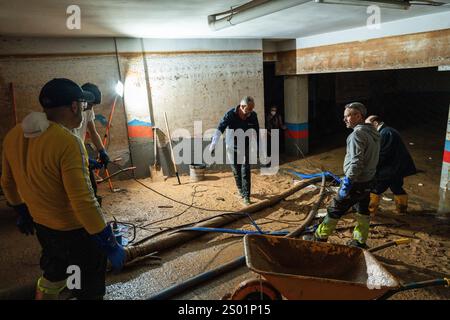 DANA-Flutungseffekte. Überschwemmungseinflüsse, Valencia, Spanien. Arbeiter pumpen Schlamm in einer Garage mit Wasserpumpe in Paiporta Stockfoto