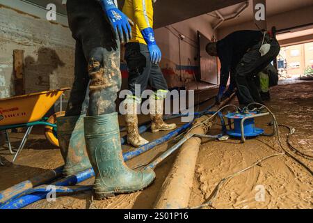 DANA-Flutungseffekte. Überschwemmungseinflüsse, Valencia, Spanien. Arbeiter pumpen Schlamm in einer Garage mit Wasserpumpe in Paiporta Stockfoto