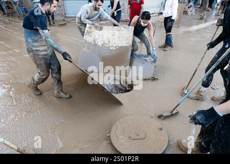 DANA-Flutungseffekte. Überschwemmungseinflüsse, Valencia, Spanien. Freiwillige und Einheimische fegen Schlamm durch die Straßen in die Kanalisation Stockfoto