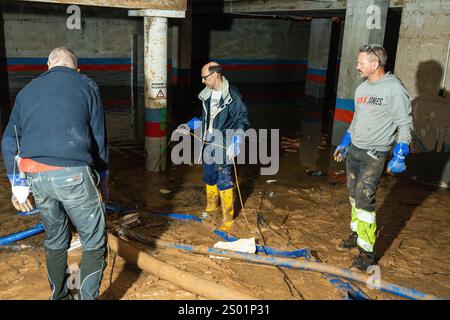 DANA-Flutungseffekte. Überschwemmungseinflüsse, Valencia, Spanien. Arbeiter pumpen Schlamm in einer Garage mit Wasserpumpe in Paiporta Stockfoto