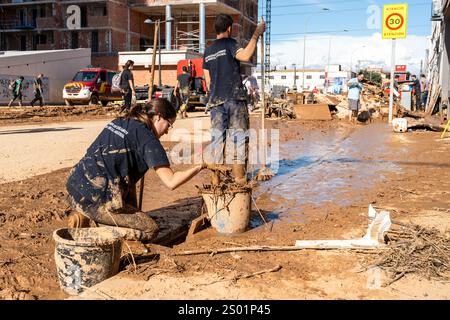 DANA-Flutungseffekte. Überschwemmungseinflüsse, Valencia, Spanien. Freiwillige reinigen Schlamm auf der Straße Stockfoto