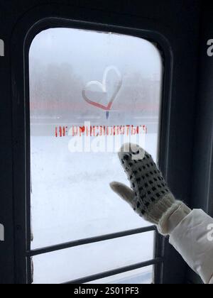 Dieses eindrucksvolle Winterfoto fängt die Einfachheit und Schönheit menschlicher Wärme vor einem frostigen Hintergrund ein. Ein Wollhandschuh berührt sanft einen beschlagenen Stockfoto